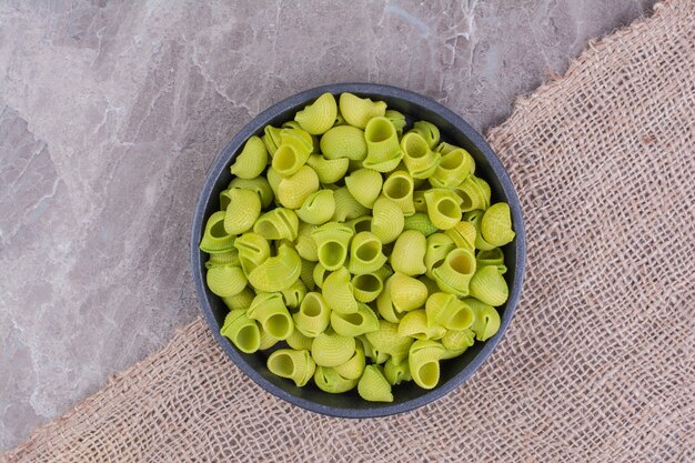 Pastas crudas verdes en un cuenco de cerámica sobre el mármol