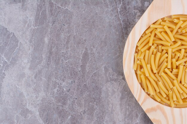 Pastas orgánicas en una taza de madera rústica en el espacio gris.