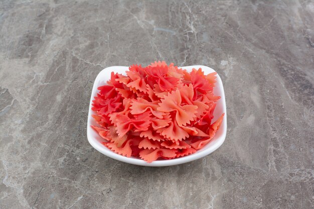 Pastas rojas en salsa de tomate en tazas de cerámica en el espacio gris.