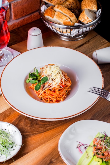 Pastbolognese con vaso de queso de compota sal pimienta y pan en la mesa