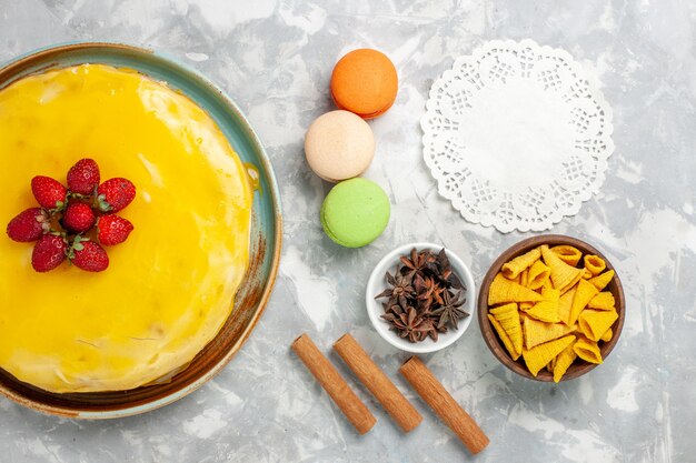 Pastel de almíbar amarillo vista superior con macarons franceses sobre fondo blanco