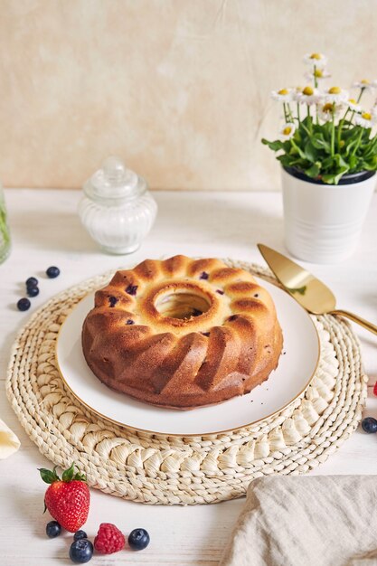 Pastel de anillo con frutas sobre una mesa blanca con superficie blanca