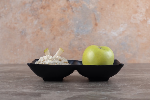 Pastel de arroz rallado y manzana en el bol, sobre la superficie de mármol