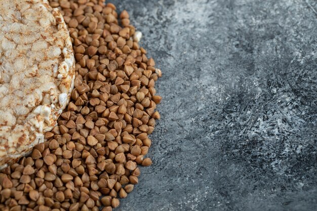 Pastel de arroz solo y trigo sarraceno crudo sobre superficie de mármol