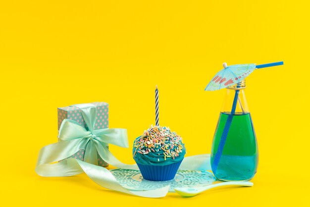 Un pastel azul de vista frontal con una pequeña caja de regalo de vela y bebida en color amarillo, bebida dulce