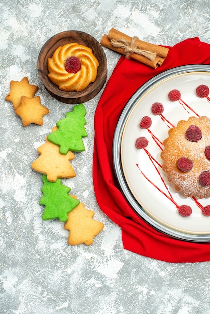 Foto gratuita pastel de baya de vista superior en placa ovalada blanca mantón rojo galletas de árbol de navidad en superficie gris