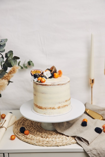 Pastel blanco con frutos rojos y maracuyá junto a una planta