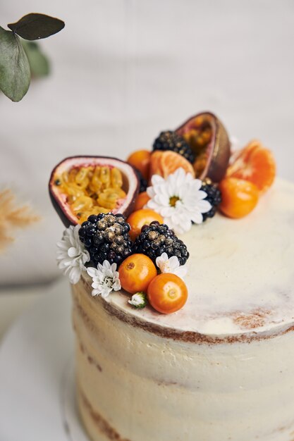 Pastel blanco con frutos rojos y maracuyá junto a una planta