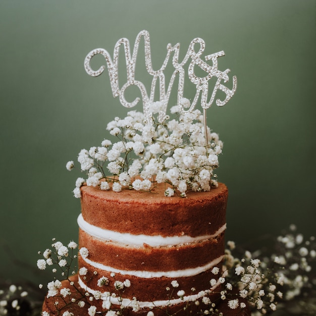 Foto gratuita pastel de bodas con decoración de paniculata y sr. y sra. topper sobre fondo verde