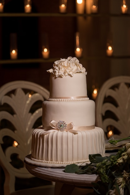 Pastel de bodas de fondant blanco de tres niveles cubierto con flores de crema de mantequilla