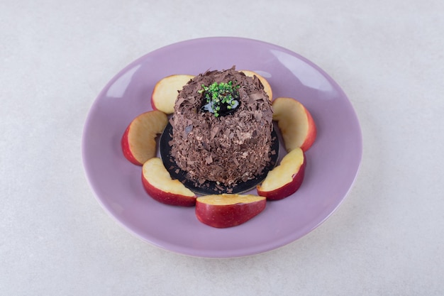 Pastel de brownie y manzanas en rodajas en un plato sobre una mesa de mármol.
