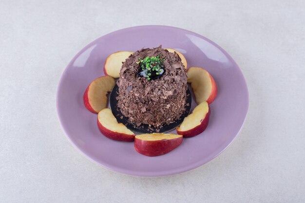 Pastel de brownie y manzanas en rodajas en un plato sobre una mesa de mármol.