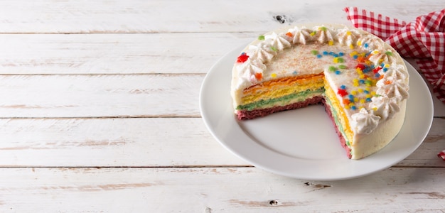 Pastel de capas de arco iris en la mesa de madera blanca