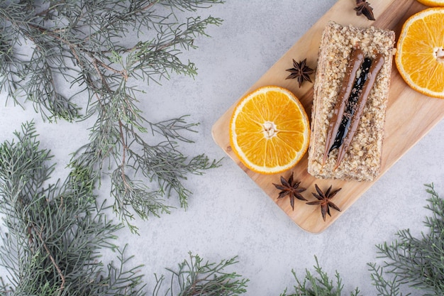 Pastel casero con clavo y rodajas de naranja sobre tabla de madera. Foto de alta calidad