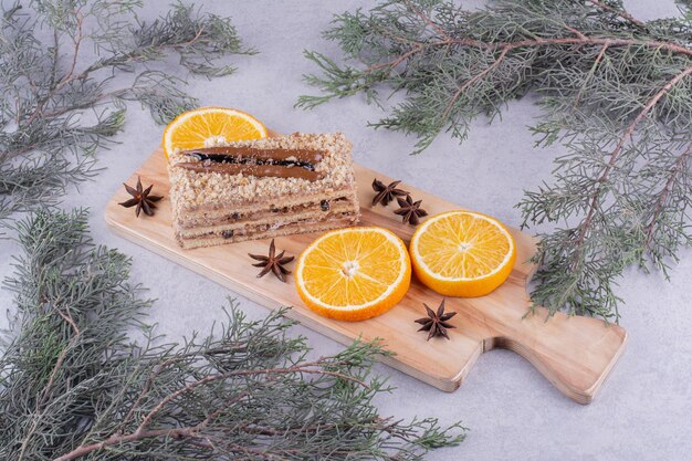 Pastel casero con clavo y rodajas de naranja sobre tabla de madera. Foto de alta calidad