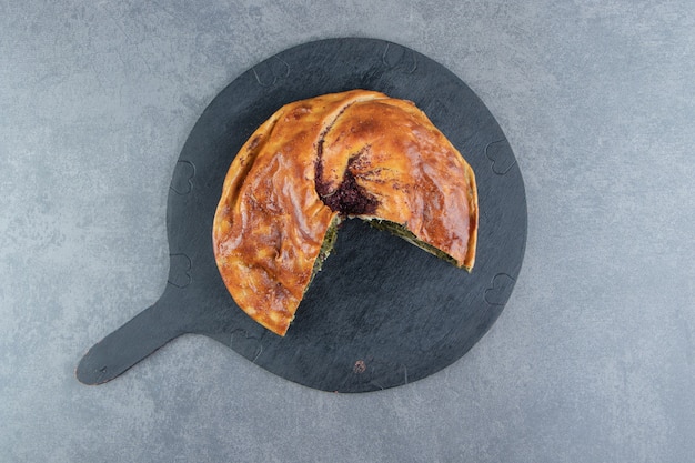 Pastel casero relleno de verduras sobre tabla de cortar negra.