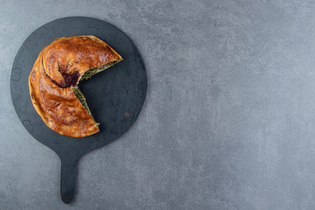 Pastel casero relleno de verduras sobre tabla de cortar negra.