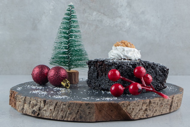 Pastel de chocolate y adornos navideños sobre una tabla de madera sobre fondo de mármol.