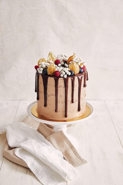 Foto gratuita pastel de chocolate aseado con pequeñas flores blancas, bayas y hojas secas