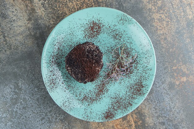 Un pastel de chocolate con cacao en polvo sobre una placa azul.