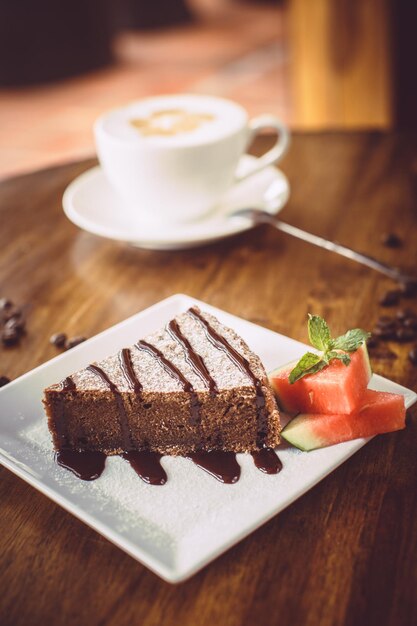 Pastel de chocolate con capuchino en una mesa de madera en un restaurante