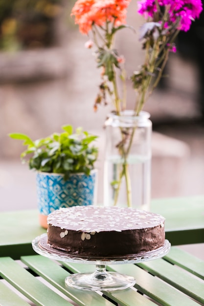 Foto gratuita pastel de chocolate decorado con rodajas de almendras en el soporte de la torta sobre la mesa