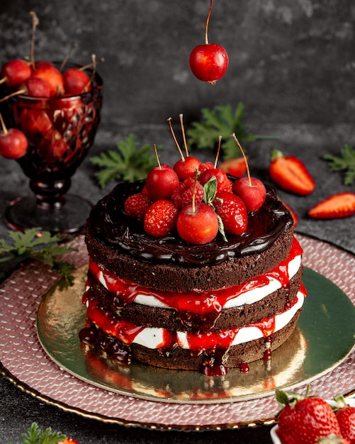 Pastel de chocolate desnudo decorado con fresas, frambuesa, manzanas pequeñas y jarabe