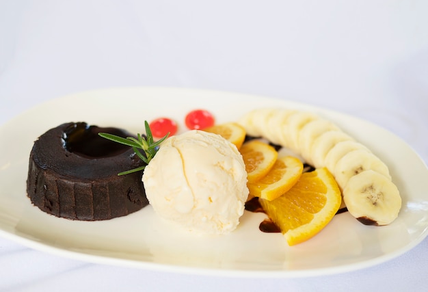 Pastel de chocolate de lava con naranja bien decorada y plátano y helado.