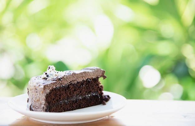 Pastel de chocolate en la mesa con jardín verde - relájese con el concepto de panadería y naturaleza