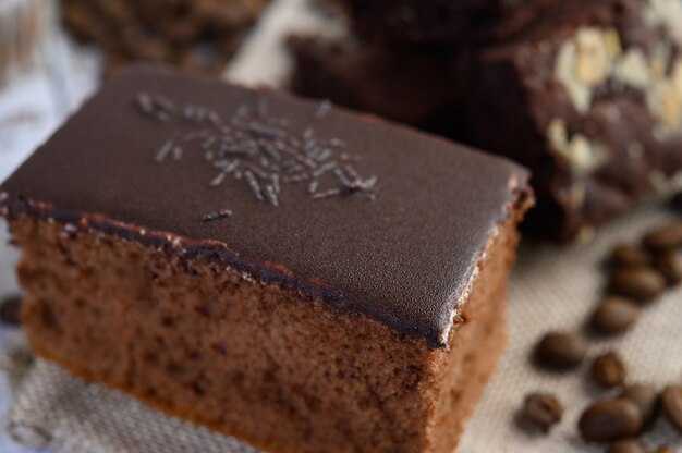 Pastel de chocolate en un plato blanco con granos de café sobre una mesa de madera