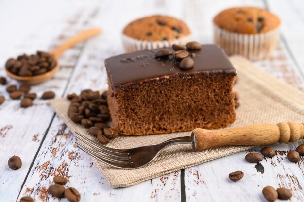 Pastel de chocolate en el saco y granos de café con un tenedor en una mesa de madera.