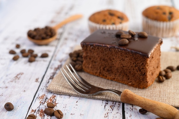 Pastel de chocolate en el saco y granos de café con un tenedor en una mesa de madera.