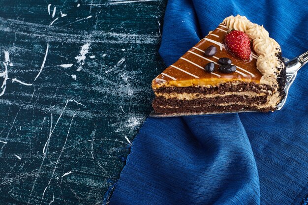 Pastel de chocolate servido con fresas sobre fondo azul.