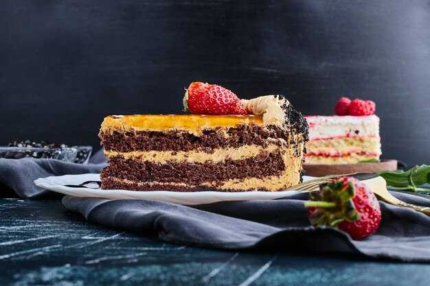 Pastel de chocolate servido con frutos rojos sobre fondo azul.