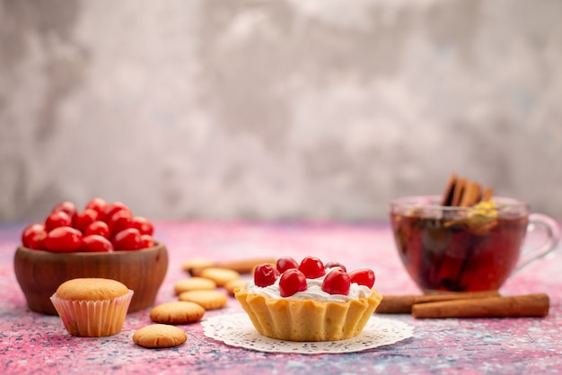 Foto gratuita pastel de crema de vista frontal con arándanos rojos frescos junto con galletas de canela y té en el brillante escritorio biscuit té dulce