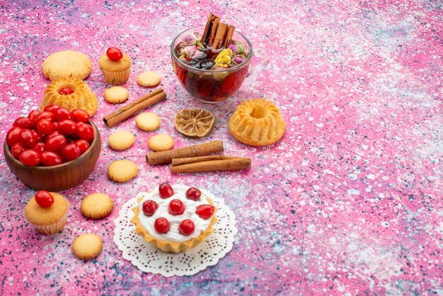 Pastel de crema de vista frontal con arándanos rojos frescos junto con galletas de canela y té en el escritorio brillante fruta dulce galleta