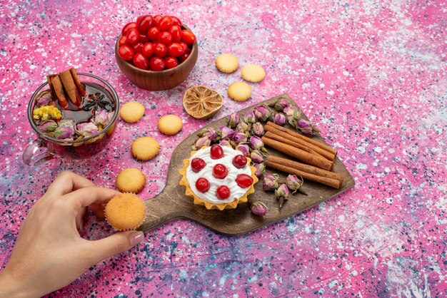 Pastel de crema de vista superior con arándanos rojos frescos junto con galletas de canela y té en la mesa brillante dulce de azúcar