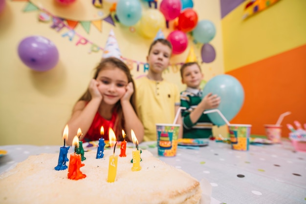 Pastel de cumpleaños cerca de niños borrosos