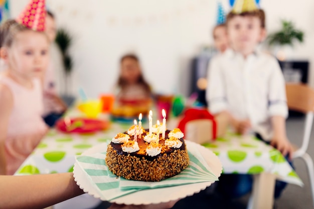 Pastel de cumpleaños con niños en el fondo