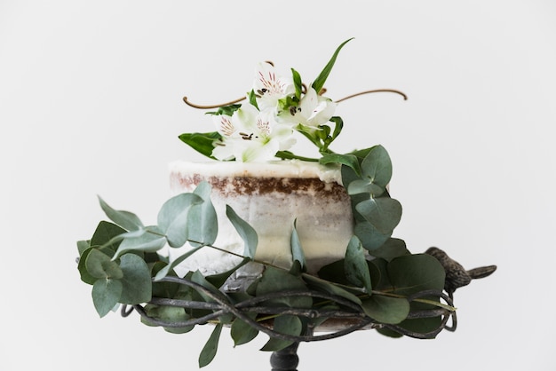 Pastel decorado con flores de alstromeria y hojas verdes sobre fondo blanco