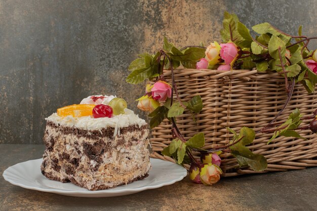 Pastel dulce con canasta de rosas sobre mesa de mármol