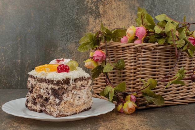 Pastel dulce con canasta de rosas sobre mesa de mármol