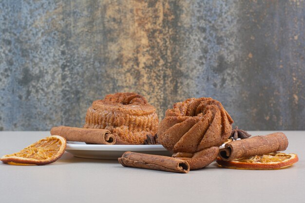 Pastel dulce con rodajas de naranja y canela en un plato blanco.