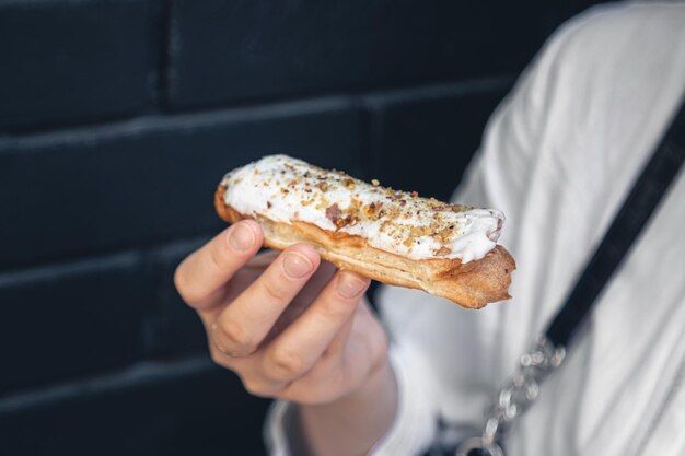 Pastel de eclair de primer plano en una mano femenina