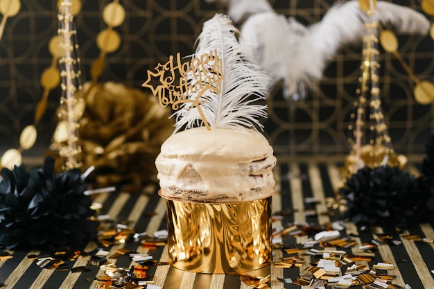 Pastel de fiesta de cumpleaños con decoración dorada y negra con varios globos.