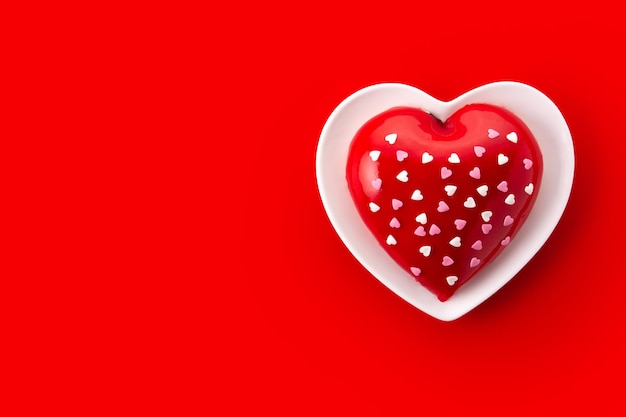 Pastel en forma de corazón para el día de San Valentín o el día de la madre sobre fondo rojo.