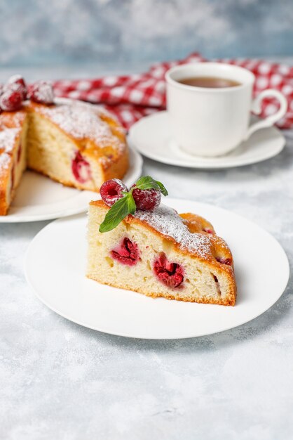 Pastel de frambuesa con azúcar en polvo y frambuesas frescas en una luz. Postre de bayas de verano.