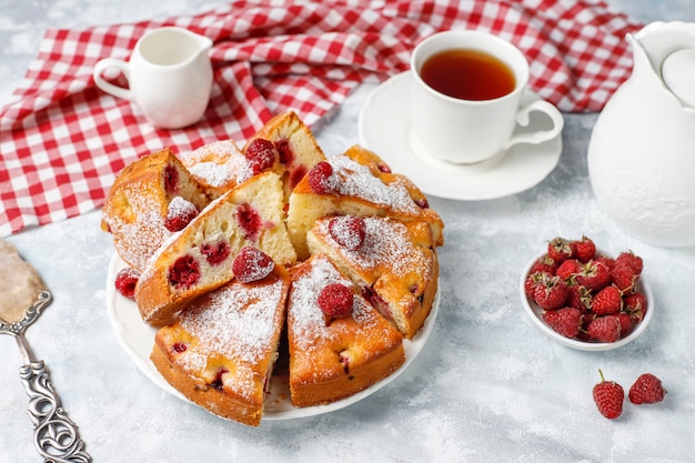 Pastel de frambuesa con azúcar en polvo y frambuesas frescas en una luz. Postre de bayas de verano.