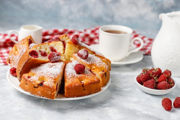 Pastel de frambuesa con azúcar en polvo y frambuesas frescas en una luz. Postre de bayas de verano.