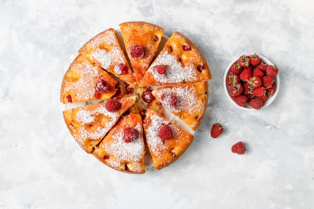 Pastel de frambuesa con azúcar en polvo y frambuesas frescas en una luz. Postre de bayas de verano.